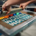 Un artisan réalise le marquage de vêtements personnalisés avec la technique de sérigraphie.