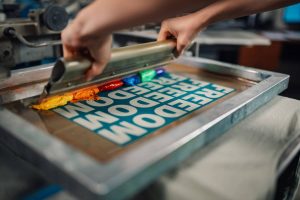 Un artisan réalise le marquage de vêtements personnalisés avec la technique de sérigraphie.
